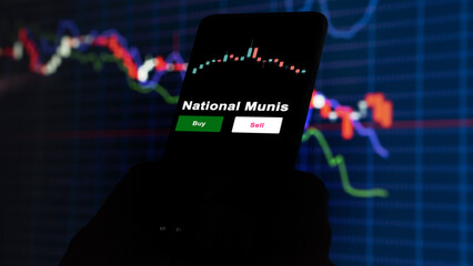 An investor's analyzing the National munis etf fund on screen. A phone shows the municipal bonds prices to invest
