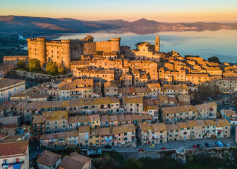 Sunset Panoramic view of the old town of Bracciano perched above the calm waters of Lake Bracciano,...