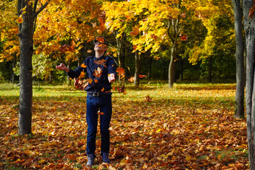 A person rejoices in the fall of leaves. A teenager admires the falling autumn maple leaves:...