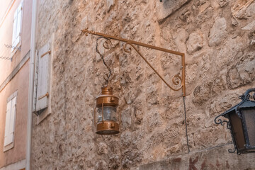 an old street lamp attached to the stone wall of an old building. Old lighting fixtures. An antique lamp.