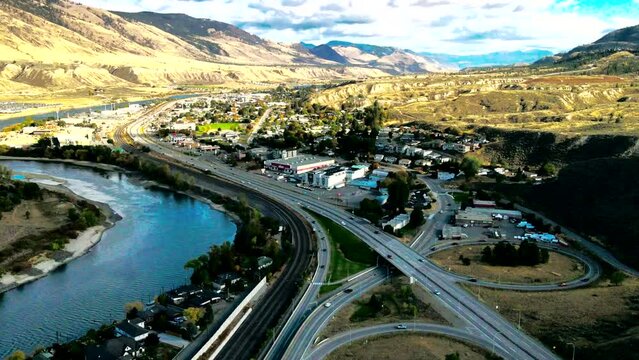 hyper-lapse dolly in drone shot of Bridges and the Highway 1 and Yellowhead Highway in Kamloops BC Canada with train trucks, the Thompson River on a Cloudy Day in a desert environment