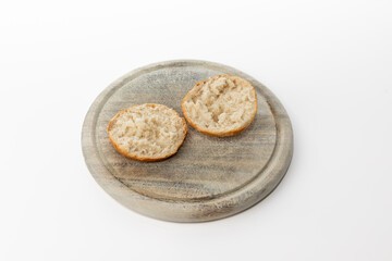 Open kaiser roll on wooden plate isolated on white background