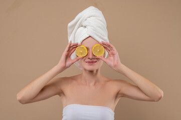 Young woman holding slices of oranges before beauty procedures