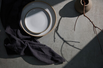 Set of ceramic porcelain plates stacked in Japanese style. Vases and dark napkins on the cement table