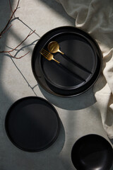 Fototapeta premium Set decoration ceramic Japanese Style with Different sizes of minimal black ceramic plates set, golden ware, and napkins on the Cement background. Japanese style 