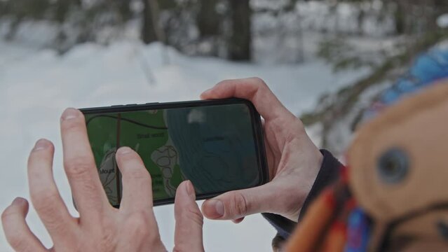 Close-up shot of unrecognizable person holding smartphone reading map on screen checking route to travel destination