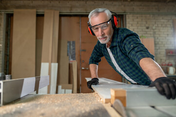 Carpenter in ear protectors working in a workshop