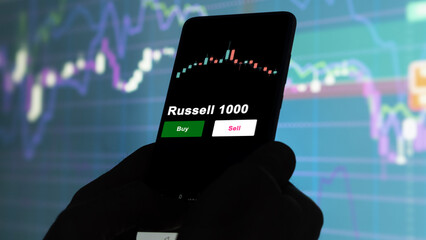 An investor's analyzing the Russell 1000 etf fund on screen. A phone shows the ETF's prices small cap smallCap to invest
