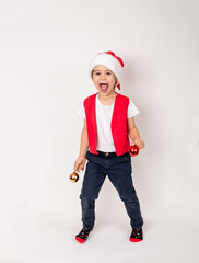 Vertical portrait of standing child in red Santa Claus hat holding in hands Christmas tree toy balls. Cute 5 year European smiling and dancing boy. New year holiday shopping concept. New Year decor