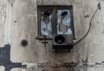 War in Ukraine. 2022 Russian invasion of Ukraine. A window with a burned-out air conditioner in an apartment building (close-up). Terror of the civilian population. War crimes