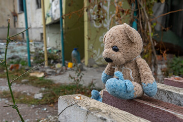 War in Ukraine. 2022 Russian invasion of Ukraine. Сhildren's toy (teddy bear) lies against the backdrop of an apartment building destroyed by shelling. Terror of the civilian population. War crimes
