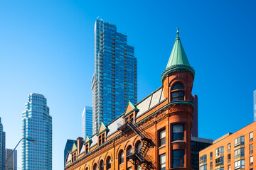 Canada, Toronto. The famous Gooderham building and the skyscrapers in the background. View of the city in the day. Modern and ancient architecture.