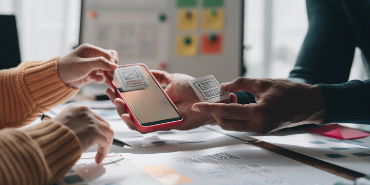 UI UX creative designer team designing wireframe layout for responsive mobile smartphone application in office