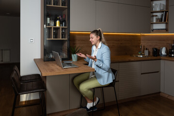 Young freelancer woman sitting at home with laptop having online job interview while she wearing...