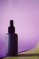 Skin care lotion or serum on purple background.