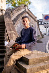 Cute teenage boy with a textbook smiling at the camera
