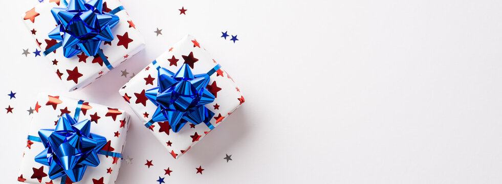 USA Independence Day concept. Top view photo of gift boxes with ribbon bows and star shaped confetti on isolated white background with copyspace
