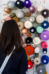 絹糸の加工サンプルや色サンプルを展示するボードを見る女性