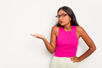 Young Indian woman isolated on white background showing a copy space on a palm and holding another hand on waist.