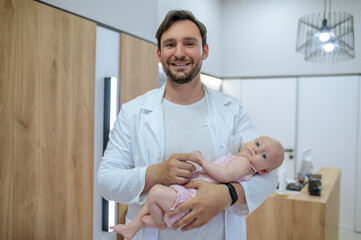 Young pediatrician posing for the camera with a neonatal patient