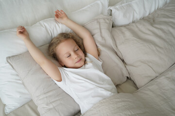 Little child girl sleeping in bed, lying on soft cotton pillow in bedroom. Healthy children's sleep