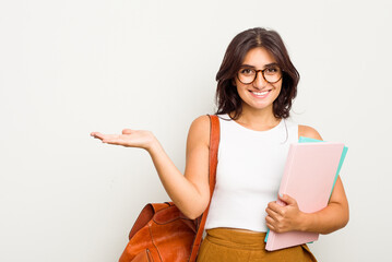 Young student Indian woman isolated on white background showing a copy space on a palm and holding another hand on waist.