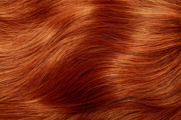 Red hair close-up as a background. Women's long orange hair. Beautifully styled wavy shiny curls....