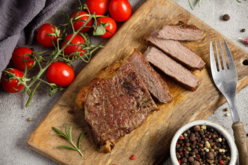 Grilled sliced beef steak well done on wooden cutting board. Top view.