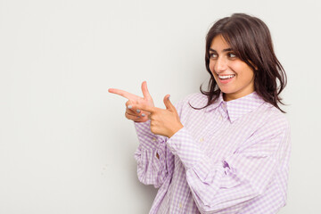 Young Indian woman isolated on white background points with thumb finger away, laughing and carefree.