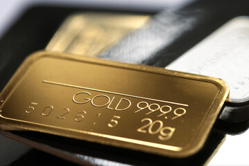 Minted gold bar weighing 50 grams on a blurred background. Selective focus.