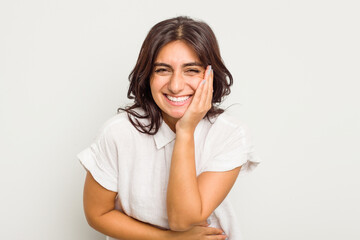 Young Indian woman isolated on white background laughs happily and has fun keeping hands on stomach.