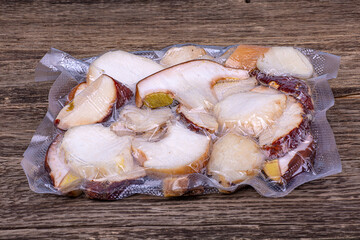Frozen porcini mushrooms in vacuum packaging on a wooden background, close-up