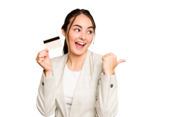 Young caucasian woman holding a credit card isolated on green chroma background points with thumb finger away, laughing and carefree.