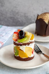 Fruit cake on a gray background. Delicious cake made with strawberry, banana, kiwi, peach and cream. Bakery products. close up