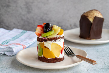 Fruit cake on a gray background. Delicious cake made with strawberry, banana, kiwi, peach and cream. Bakery products. close up