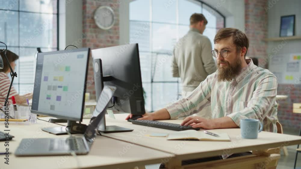 Poster Portrait of Creative Bearded White Man with Glasses Focused While Using Computer in Bright Spacious Office. Marketing Manager Building a New Strategy. Dolly Shot.