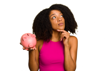 Young African American woman holding a piggy bank isolated looking sideways with doubtful and skeptical expression.