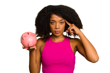 Young African American woman holding a piggy bank isolated pointing temple with finger, thinking, focused on a task.