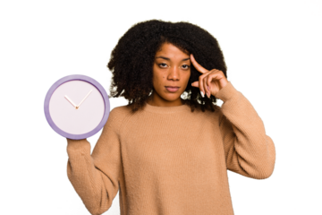 Young African American holding a clock isolated pointing temple with finger, thinking, focused on a task.