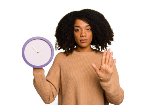 Young African American holding a clock isolated standing with outstretched hand showing stop sign, preventing you.