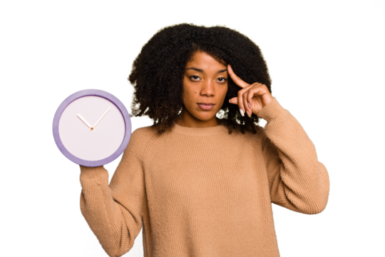 Young African American holding a clock isolated pointing temple with finger, thinking, focused on a task.