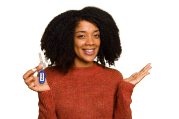 Young African american woman holding home keys isolated showing a copy space on a palm and holding another hand on waist.