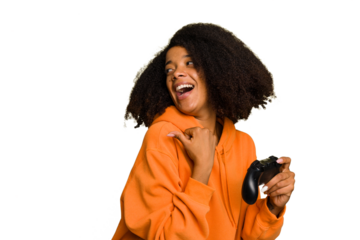 Young African American woman holding a game controller isolated points with thumb finger away, laughing and carefree.