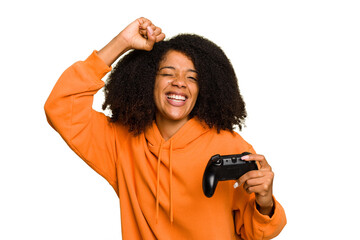 Young African American woman holding a game controller isolated raising fist after a victory, winner concept. © Asier