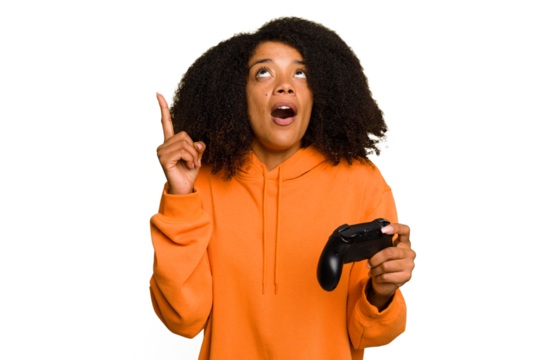 Young African American woman holding a game controller isolated pointing upside with opened mouth.
