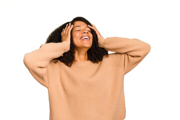 Young African American woman isolated laughs joyfully keeping hands on head. Happiness concept.