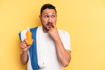 Young latin man ready to go to the beach holding a solar skin protection isolated relaxed thinking about something looking at a copy space.