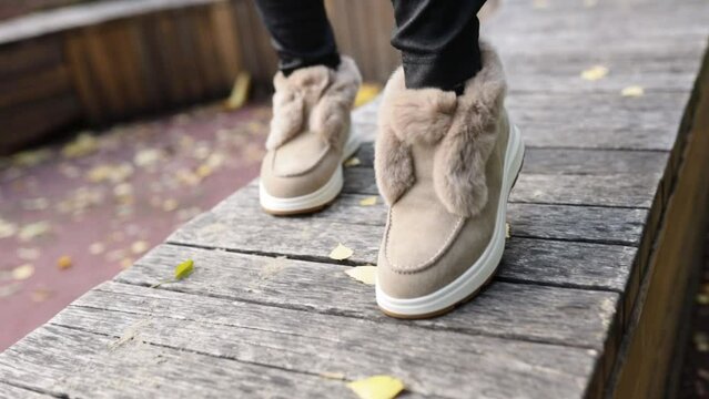 Stylish trendy beige autumn-winter shoes with soft light fur and rhinestones on the gray paving stones