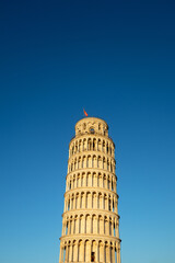 Fototapeta na wymiar Pisa tower sunset light colors against blue sky low angle view