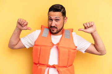 Young latin beach watcher wearing a lifejacket isolated feels proud and self confident, example to...
